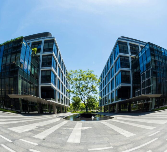 Modern office buildings flanking a central green courtyard.
